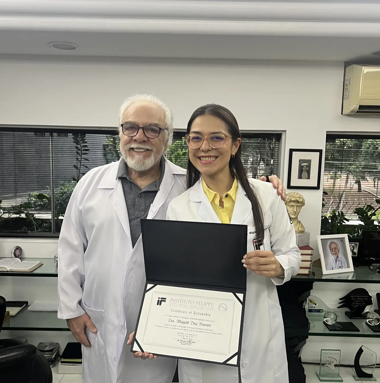La Dra. Migzaid Díaz, con delantal del Instituto Felippu, sostiene su certificado.